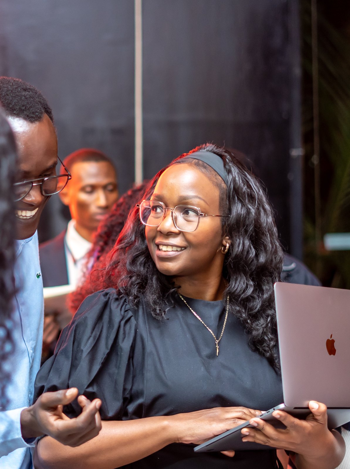 Agnes Muthoni smiling with a laptop among builders at the Claude Community Hackathon in Nairobi, Kenya